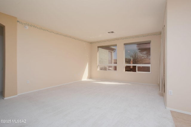 empty room featuring light colored carpet, visible vents, and baseboards