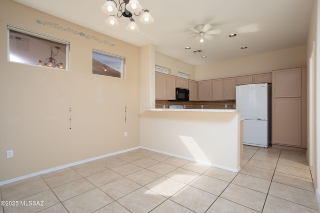 kitchen featuring light tile patterned floors, a ceiling fan, freestanding refrigerator, black microwave, and a peninsula