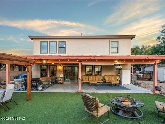 back house at dusk with a yard, a patio area, and an outdoor living space with a fire pit