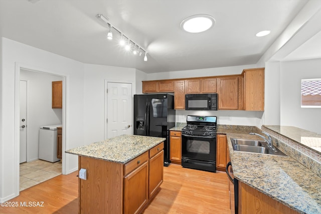 kitchen featuring light hardwood / wood-style flooring, sink, light stone countertops, a center island, and black appliances