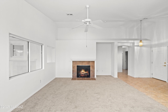 unfurnished living room featuring vaulted ceiling, ceiling fan, a fireplace, and light tile patterned flooring