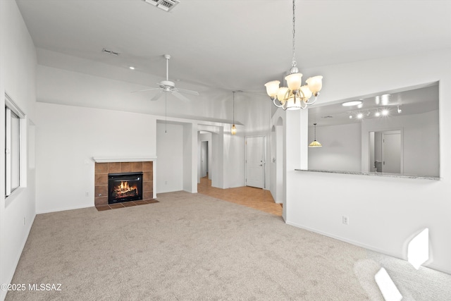 unfurnished living room with ceiling fan with notable chandelier, a tile fireplace, light colored carpet, and vaulted ceiling