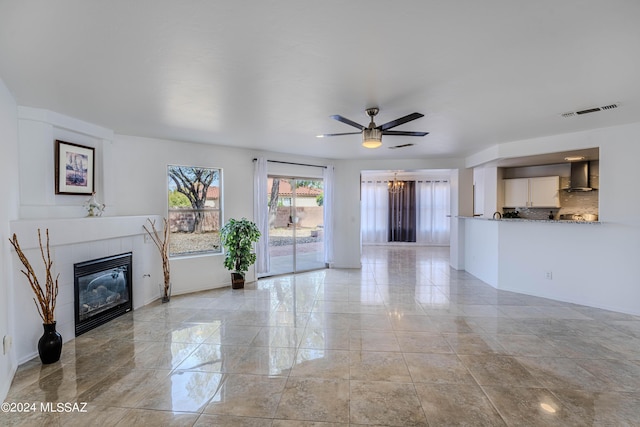 unfurnished living room featuring a tiled fireplace and ceiling fan