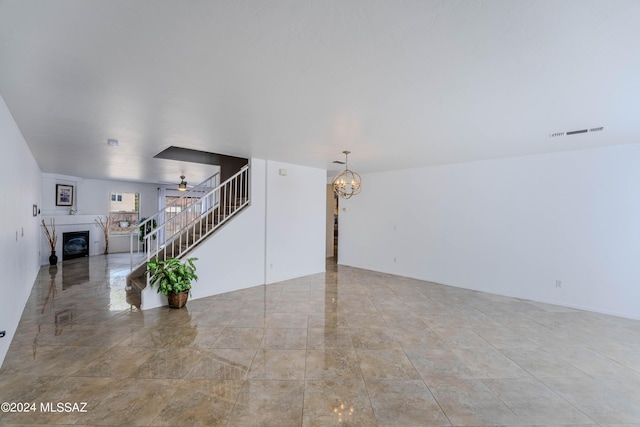 unfurnished living room featuring ceiling fan with notable chandelier