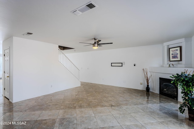 unfurnished living room featuring a tiled fireplace and ceiling fan