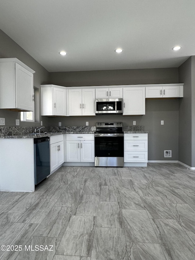 kitchen featuring stainless steel appliances, dark stone counters, and white cabinets