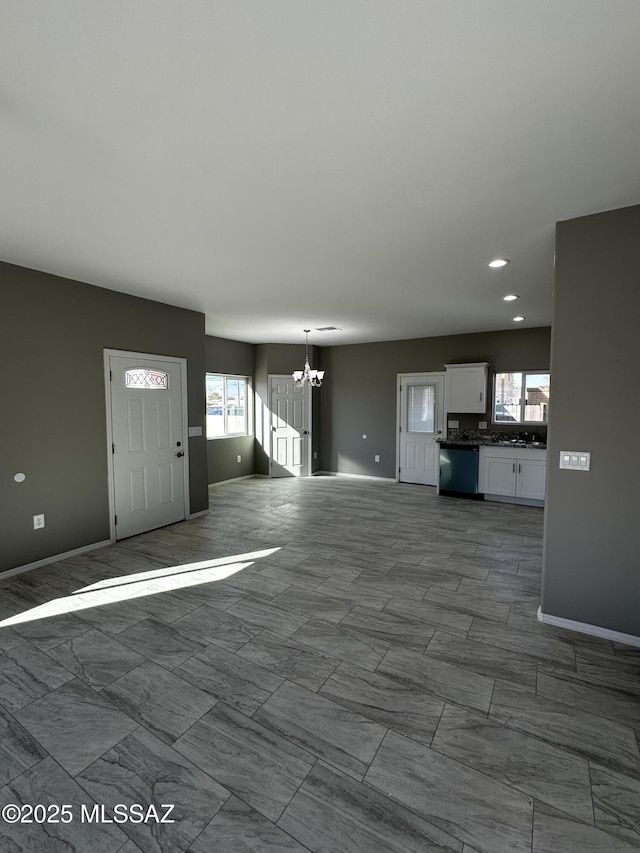 unfurnished living room featuring a chandelier