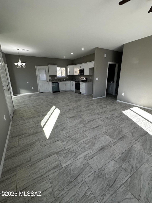 unfurnished living room with ceiling fan with notable chandelier