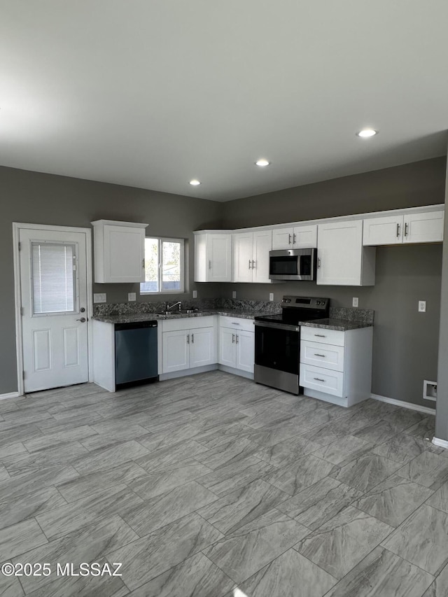 kitchen with white cabinetry, sink, dark stone countertops, and appliances with stainless steel finishes