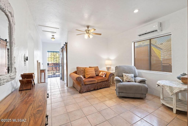 tiled living room featuring ceiling fan, a barn door, and a wall unit AC