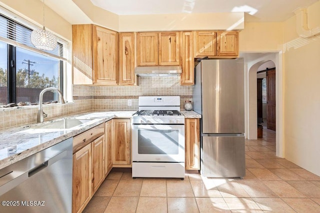 kitchen featuring pendant lighting, sink, appliances with stainless steel finishes, light stone counters, and decorative backsplash