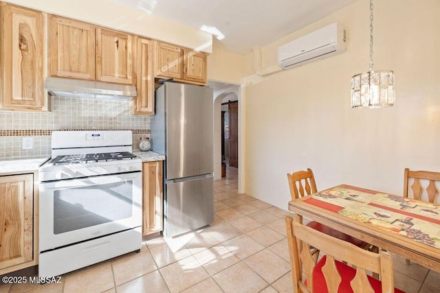 kitchen featuring a wall mounted air conditioner, stainless steel refrigerator, white gas range, decorative backsplash, and hanging light fixtures