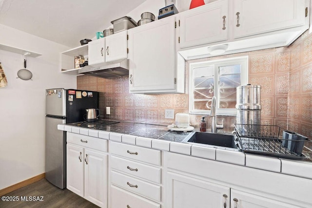 kitchen featuring stainless steel refrigerator, white cabinetry, dark hardwood / wood-style floors, tasteful backsplash, and tile counters