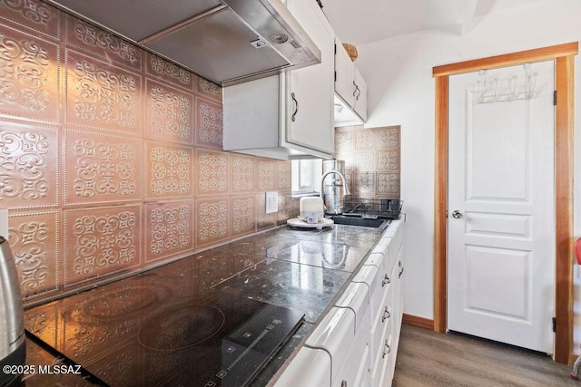 kitchen featuring sink, hardwood / wood-style flooring, custom range hood, white cabinets, and decorative backsplash