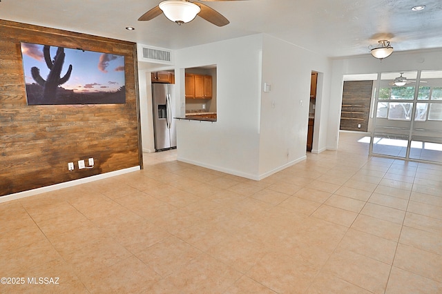 empty room featuring ceiling fan and wooden walls