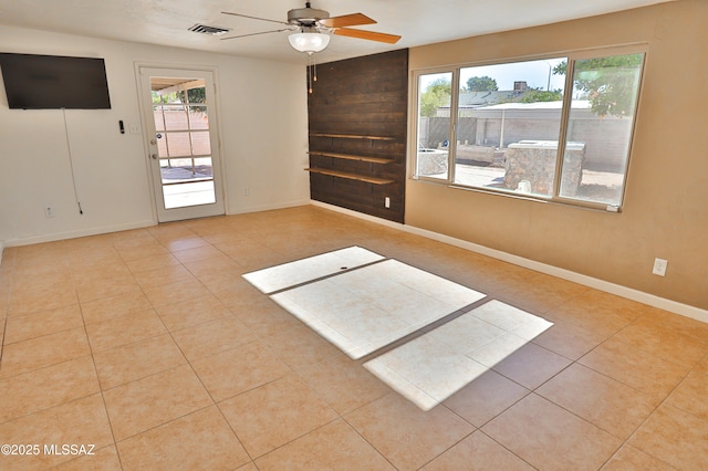 empty room featuring a wealth of natural light, ceiling fan, and light tile patterned floors