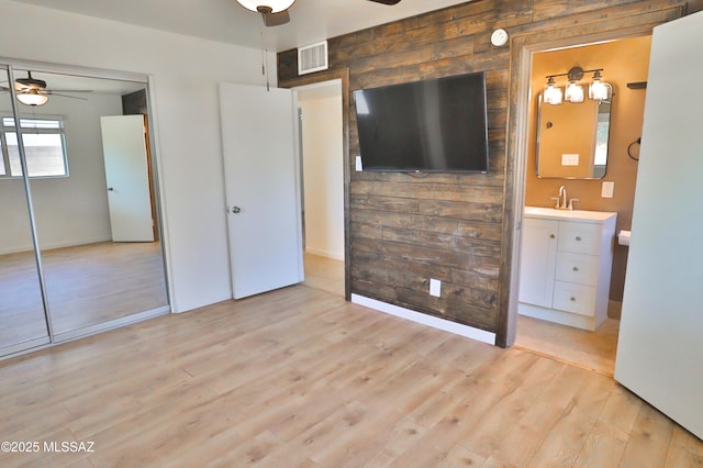 unfurnished bedroom featuring sink, light hardwood / wood-style flooring, a closet, and ceiling fan