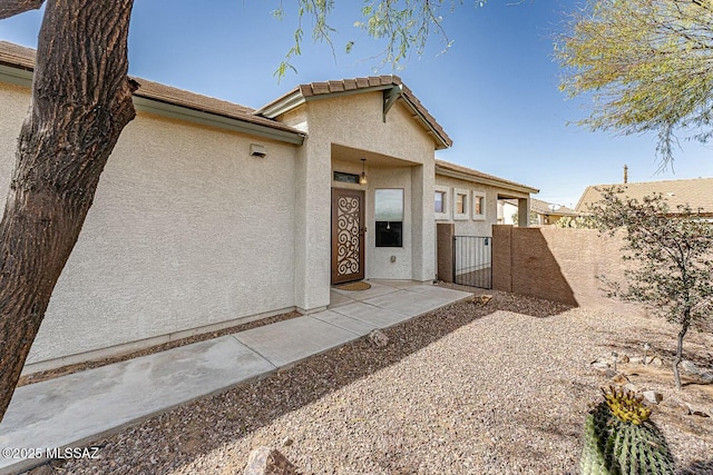 view of front facade featuring a gate, fence, and stucco siding