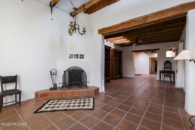 living room with beam ceiling, ceiling fan, a tile fireplace, and dark tile patterned floors