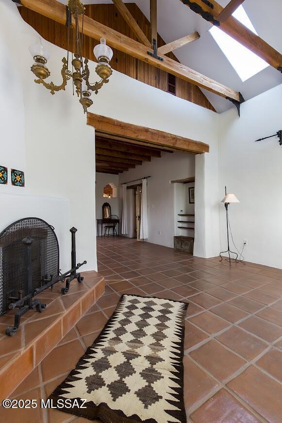 living room featuring a chandelier, beamed ceiling, dark tile patterned flooring, and high vaulted ceiling