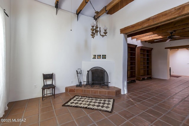 tiled living room featuring a tile fireplace, beam ceiling, and ceiling fan