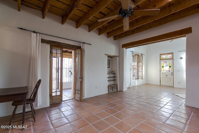 unfurnished room featuring ceiling fan, beamed ceiling, light tile patterned floors, and wooden ceiling