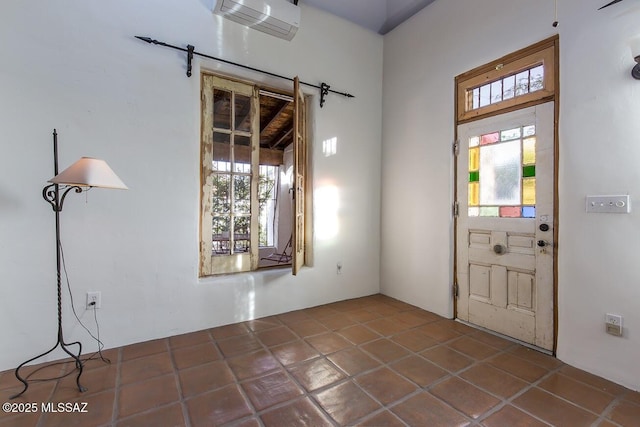 foyer entrance with an AC wall unit, plenty of natural light, and tile patterned floors