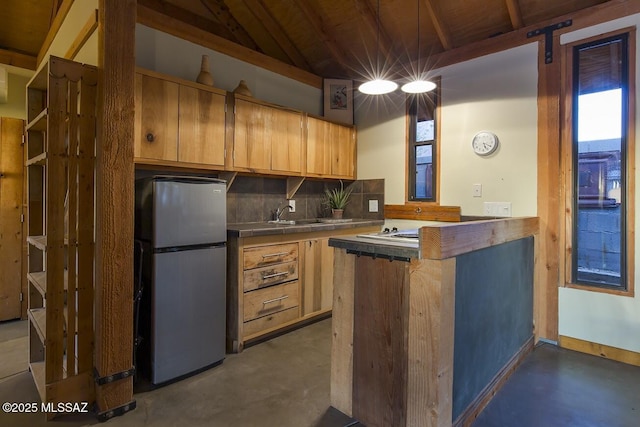 kitchen with kitchen peninsula, vaulted ceiling, stainless steel fridge, sink, and tasteful backsplash