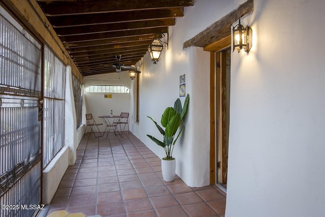 corridor with vaulted ceiling with beams and light tile patterned floors