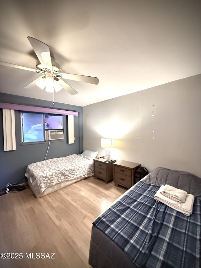 bedroom featuring cooling unit, light hardwood / wood-style floors, and ceiling fan