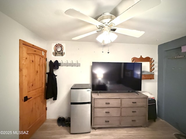 bedroom with stainless steel fridge, ceiling fan, and light hardwood / wood-style flooring