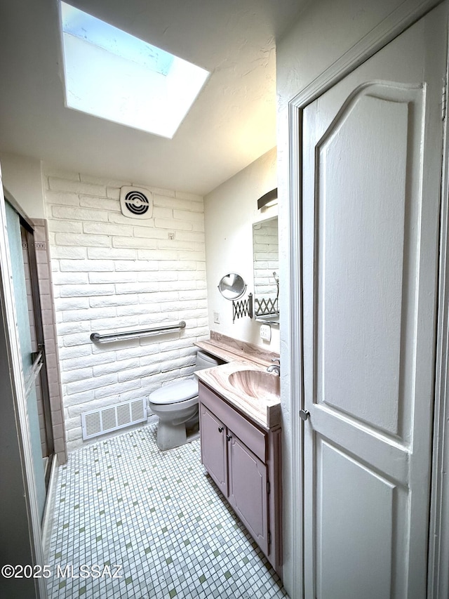 bathroom with tile patterned floors, vanity, toilet, and a skylight