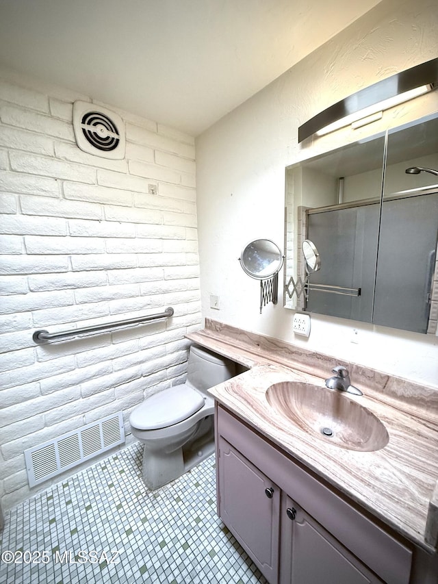 bathroom featuring vanity, tile patterned flooring, toilet, and brick wall