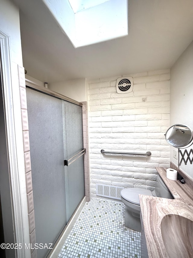 bathroom featuring brick wall, toilet, a shower with door, and vanity