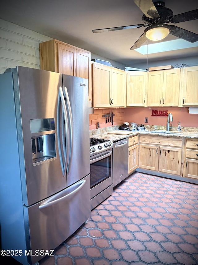 kitchen featuring sink, ceiling fan, stainless steel appliances, light stone countertops, and light brown cabinets