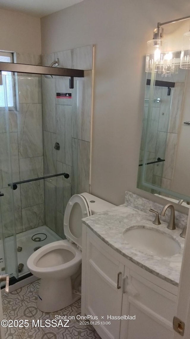 bathroom featuring vanity, toilet, an enclosed shower, and tile patterned flooring