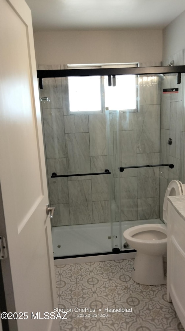 bathroom featuring tile patterned flooring, vanity, a shower with door, and toilet