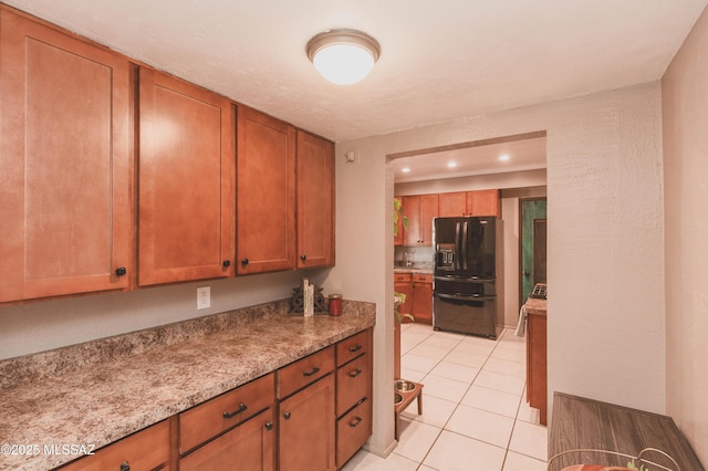 kitchen featuring light stone countertops, light tile patterned floors, and black fridge with ice dispenser