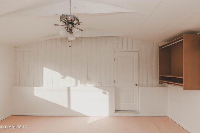 bonus room featuring ceiling fan, lofted ceiling, and wooden walls