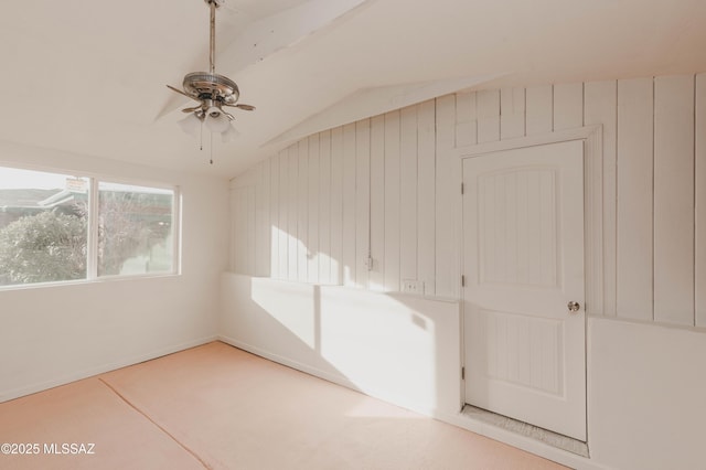 interior space with lofted ceiling, ceiling fan, and wood walls