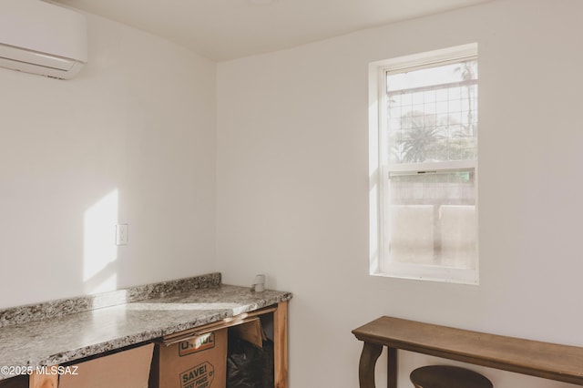 kitchen featuring light stone counters and a wall unit AC