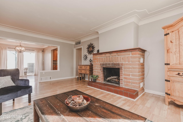 living room featuring crown molding, wood-type flooring, a notable chandelier, and a fireplace