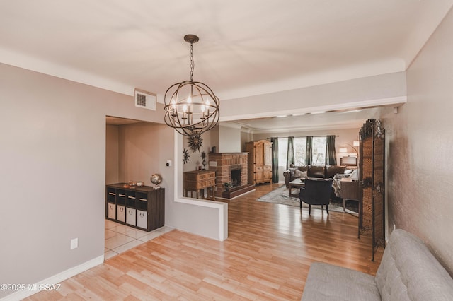 dining space featuring an inviting chandelier, a fireplace, and light hardwood / wood-style floors