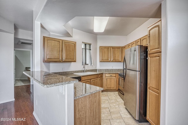 kitchen with a breakfast bar, sink, kitchen peninsula, stone counters, and stainless steel appliances