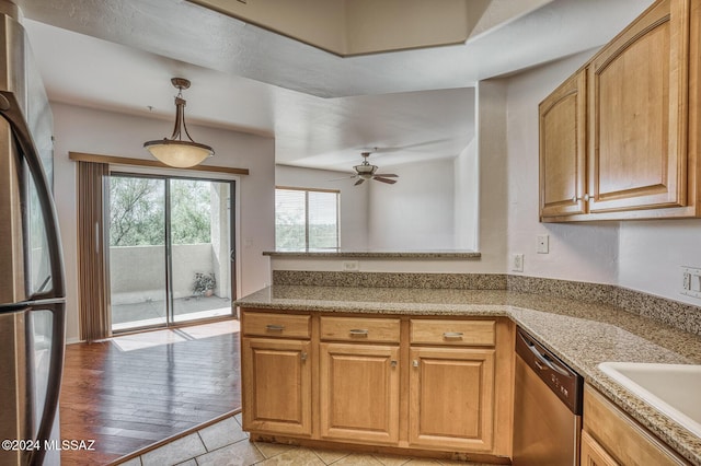 kitchen featuring pendant lighting, ceiling fan, stainless steel appliances, light stone counters, and light wood-type flooring