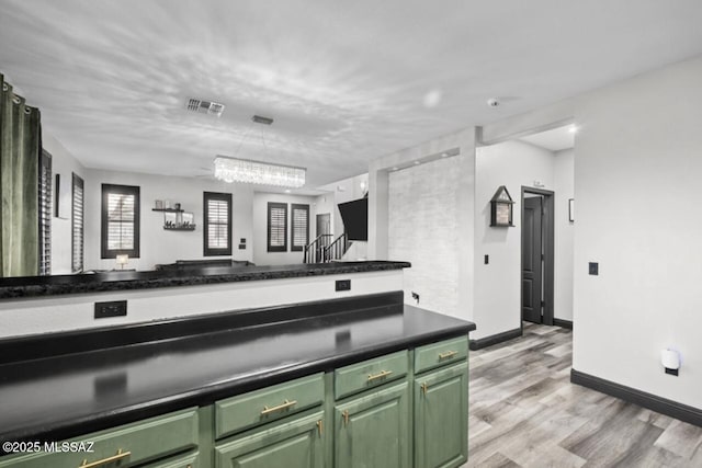 kitchen featuring green cabinets, light wood-style flooring, visible vents, and dark countertops