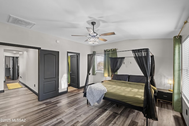 bedroom featuring visible vents, baseboards, wood finished floors, a ceiling fan, and vaulted ceiling