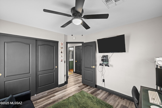 bedroom featuring baseboards, visible vents, wood finished floors, and a ceiling fan