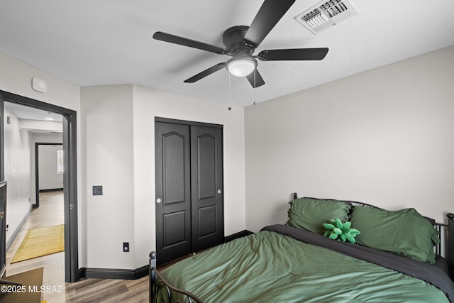 bedroom featuring a closet, visible vents, baseboards, ceiling fan, and light wood-type flooring