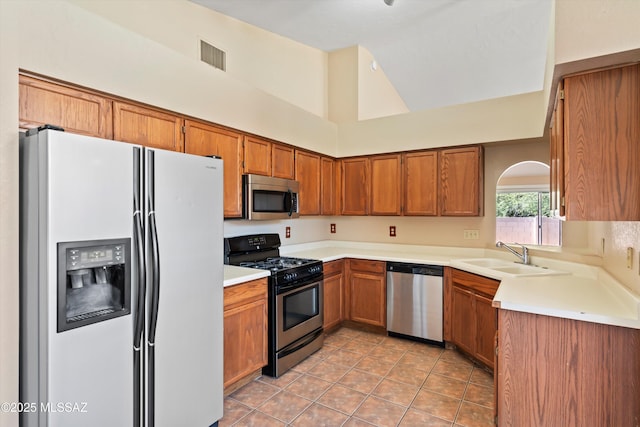 kitchen with a high ceiling, appliances with stainless steel finishes, sink, and light tile patterned floors